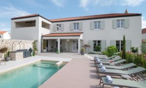 a villa with a swimming pool and lounge chairs at Luxury Villa Marca heated pool 36m2 in Nin