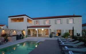 a villa with a swimming pool and lounge chairs at Luxury Villa Marca heated pool 36m2 in Nin