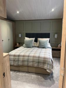 ein Schlafzimmer mit einem großen Bett mit blauen Kissen in der Unterkunft Kingfisher Lodge - Lakeside Lodge With Hot Tub in Woodhall Spa