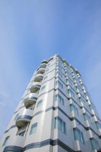 a tall white building with windows and a blue sky at Hotel Meijiya in Hamamatsu