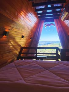a bedroom with a bed and a window with a view at Chalés Vista dei Monti in Dois Lajeados