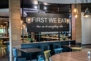 a restaurant with tables and chairs and a sign that reads first we eat at Kents Hill Park Training & Conference Centre in Milton Keynes