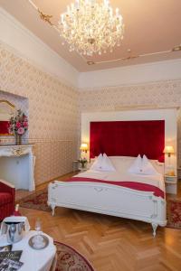 a bedroom with a large bed and a chandelier at Pertschy Palais Hotel in Vienna