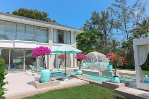 une maison avec une piscine et un parasol dans l'établissement Beachfront Luxury villa near Banyan Tree, à Layan Beach