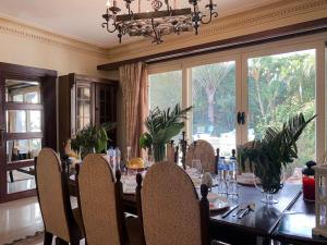 a dining room with a table with chairs and a large window at Luxury villa with swimming pool and garden in Sheikh Zayed