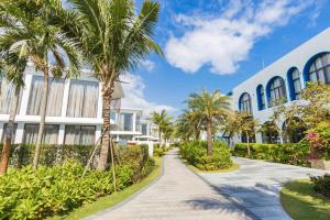 une passerelle devant un bâtiment planté de palmiers dans l'établissement Hoi An Wyndham Beachfront Resort 3 bedroom pool villa, à Hà Quảng (1)