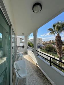 a balcony with white chairs and a palm tree at Marianna Hotel Apartments in Limassol