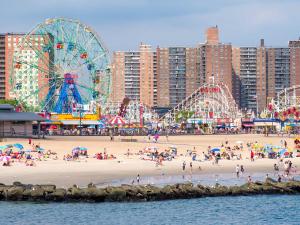 a group of people on a beach with ferris wheel at Bay Ridge ApartHotel in Brooklyn