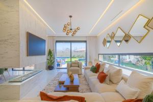 a living room with a white couch and a tv at Villa Elysée - Piscine et jardin Privée Sans vis-à-vis Wifi HD in Sraghna