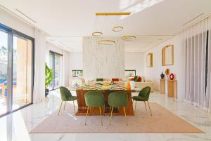 a living room with a dining table and green chairs at Villa Elysée - Piscine et jardin Privée Sans vis-à-vis Wifi HD in Sraghna