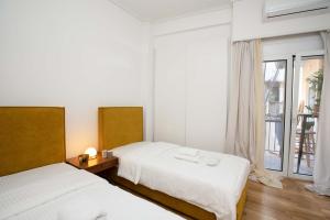 dwa łóżka w pokoju z oknem w obiekcie O&O Group Ruby's Urban Residence Koukaki w Atenach