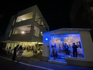 a group of people standing outside of a building at night at I FINK a HOUSE in Okayama