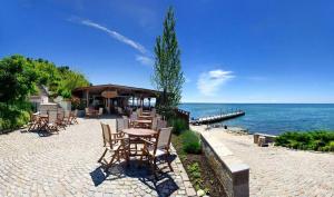 a patio with tables and chairs next to the water at Apartmány Bulharsko Sveti Vlas - Garden of Eden in Sveti Vlas
