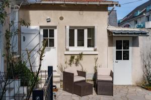 ein kleines Haus mit zwei Stühlen und einer Tür in der Unterkunft Maison clim jardin Tours centre 8 personnes 4 chambres in Tours