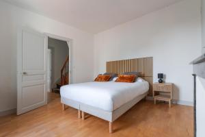 ein Schlafzimmer mit einem weißen Bett und orangefarbenen Kissen in der Unterkunft Maison clim jardin Tours centre 8 personnes 4 chambres in Tours
