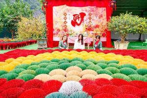 three girls standing in front of a large display of flowers at New Day Homestay in Ninh Binh