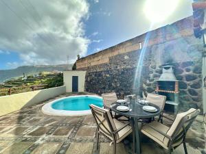 un patio con tavolo e sedie accanto alla piscina di Casa Dalia a La Orotava