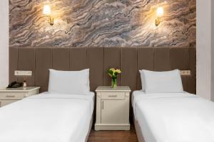 伊斯坦布尔瓦里德酒店的两张带白色床单和花瓶的床