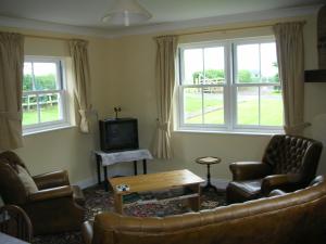 un salon avec un canapé, des chaises et des fenêtres dans l'établissement Watermill Farm Cottages, à Metheringham