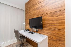 a desk with a computer monitor on a wooden wall at Fusion Hotel em Brasília 48635 in Brasilia