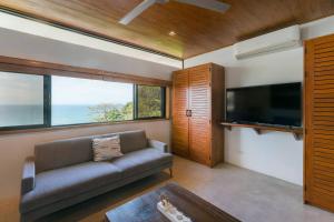 a living room with a couch and a flat screen tv at Casa Colibri - Stunning ocean view in Santa Teresa Beach