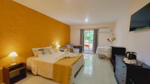 a bedroom with a large bed with a yellow wall at Hotel El Cid in Villa Carlos Paz