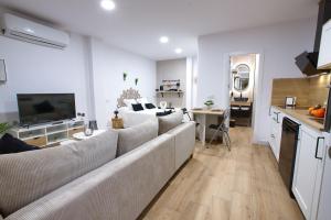 a living room with a large couch and a kitchen at Cuencaloft el Rincón especial de Cuenca in Cuenca