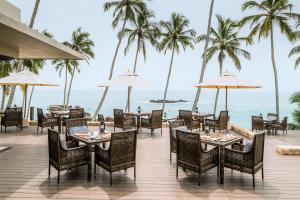 a restaurant on the beach with palm trees and the ocean at Anantara Peace Haven Tangalle Resort in Tangalle