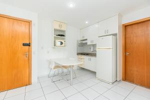 a white kitchen with a table and a refrigerator at Premier Hotel de Brasília 67961 in Brasilia