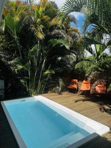 a swimming pool with two chairs and palm trees at Villa Ti Gîte - Piscine privée in Le Marin