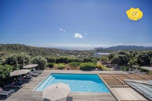 a swimming pool with chairs and umbrellas on a deck at Villa d’exception 4 chambres, piscine, vue mer in Porto-Vecchio