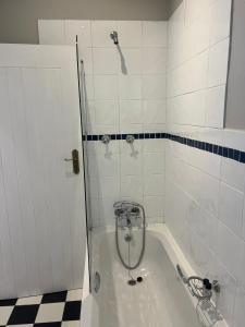 a bath tub with a shower in a bathroom at Bloom and Berry Cottage in Hallack Rock