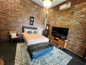 a bedroom with a brick wall with a bed and a television at Pendopo Nilam Den Erwin in Karanggan-kulon
