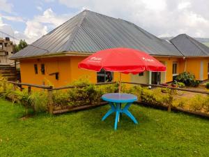 a blue table with a red umbrella in front of a house at Kay Guest house kabale in Kabale