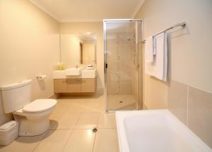 
a white toilet sitting next to a bath tub at Direct Hotels - Villas on Rivergum in Emerald
