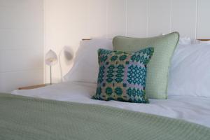 a bed with white sheets and a pillow on it at Murmur y Coed in Newborough