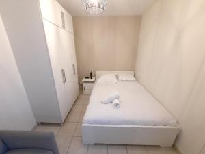 a small bedroom with a white bed and a chair at L'Apollinaire - 34m2 avec balcon et parking privé in Saint-Apollinaire