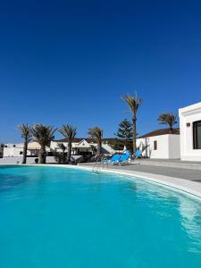 ein großer Swimmingpool mit zwei Liegen und Palmen in der Unterkunft Villa Blanca Nudist Exclusive in Charco del Palo