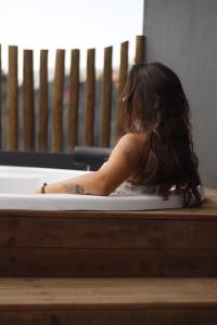 a woman with a tattoo sitting in a bath tub at Casa Beija-flor no Vale do Capão in Palmeiras