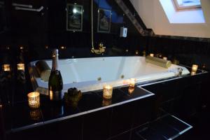 a bath tub with two bottles of wine and candles at Apartmani Vivaldi Niš in Niš