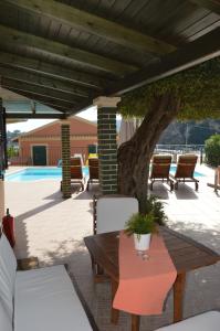 a patio with a table and chairs and a tree at Akis Apartments in Paleokastritsa