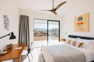 a bedroom with a bed and a desk and a window at Moonlight Mile By The Cohost Company in Pioneertown +90 photos
