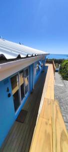 a blue building with a wooden deck next to the ocean at Hartklop Luxury Self Catering Guesthouse in Linkside