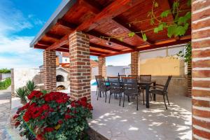 a patio with a table and chairs and flowers at Villa Ivan in Pridraga