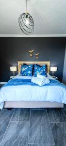 a bedroom with a large bed with blue sheets and blue pillows at Hartklop Luxury Self Catering Guesthouse in Linkside