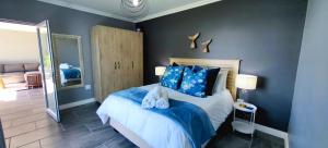 a bedroom with a bed with blue walls and a mirror at Hartklop Luxury Self Catering Guesthouse in Linkside