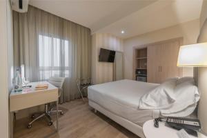 ein Hotelzimmer mit einem Bett, einem Schreibtisch und einem Computer in der Unterkunft Hesperia Murcia Centro in Murcia