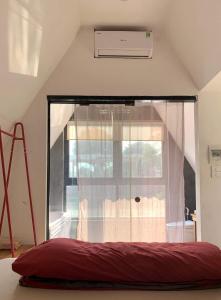 a bed in a room with a large window at Kayla Homestay - Bungalow Rose Đôi in Ba Vì
