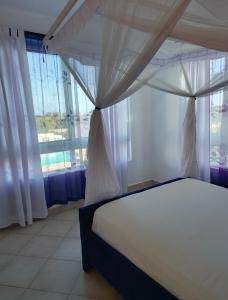 a bedroom with a bed and a large window at Modern Couzy Suites in Malindi +19 photos