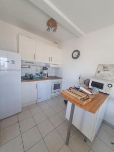 una cucina con elettrodomestici bianchi e tavolo in legno di agreable appartement situe en front de mer a Soulac-sur-Mer